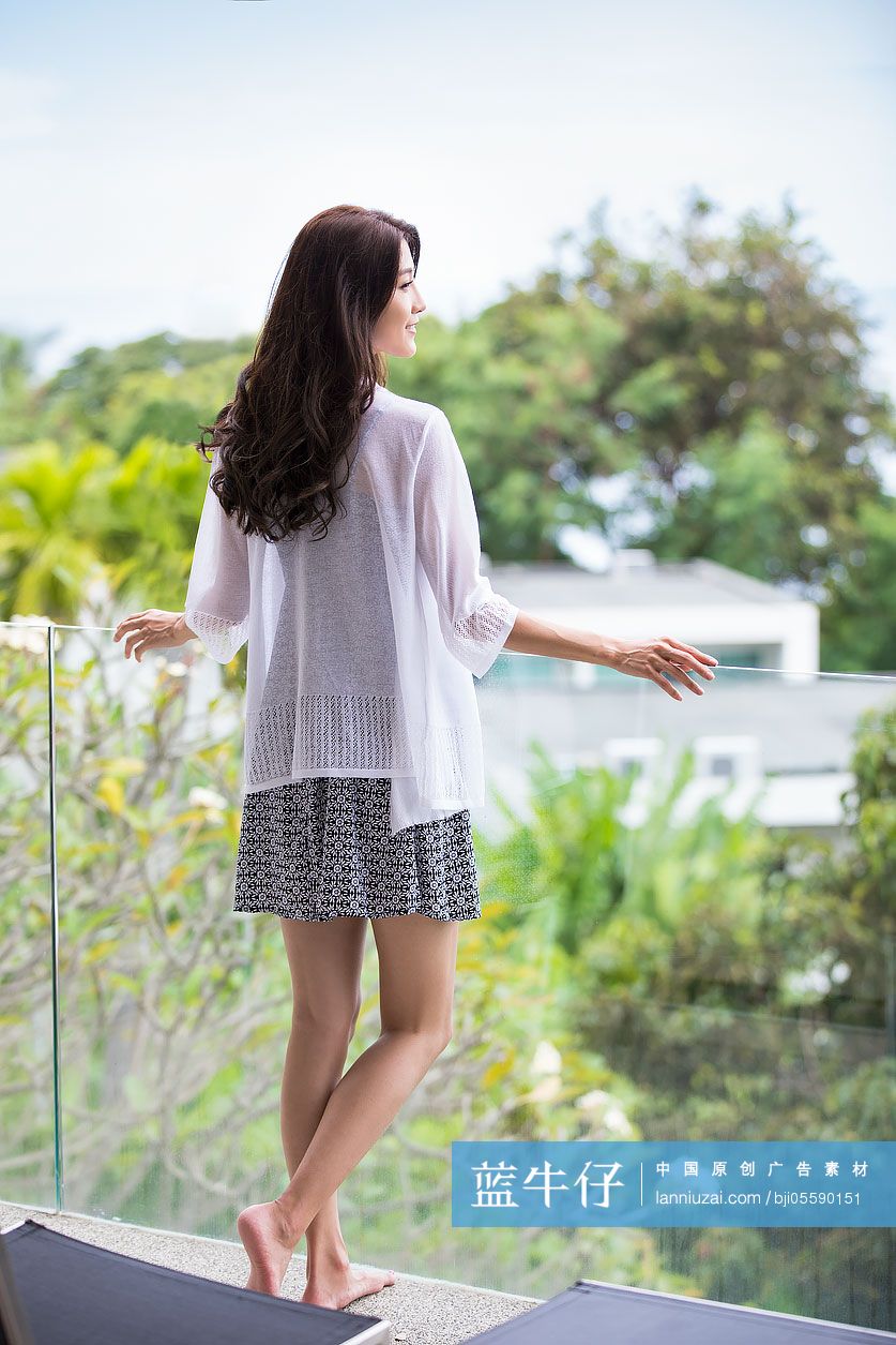 快乐的年轻女子在阳台上看风景