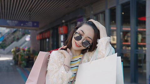 Cheerful young Chinese woman walking with shopping bags,4K