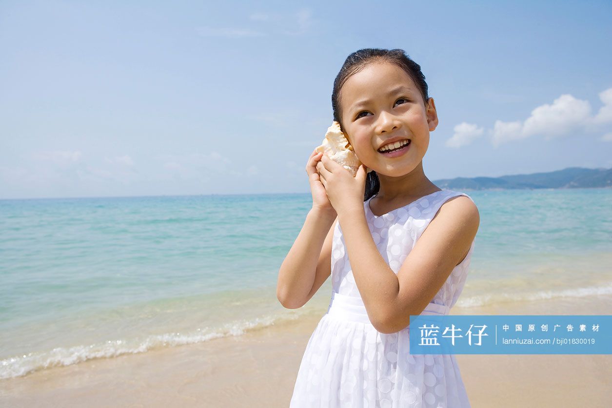 小女孩在海边听海螺