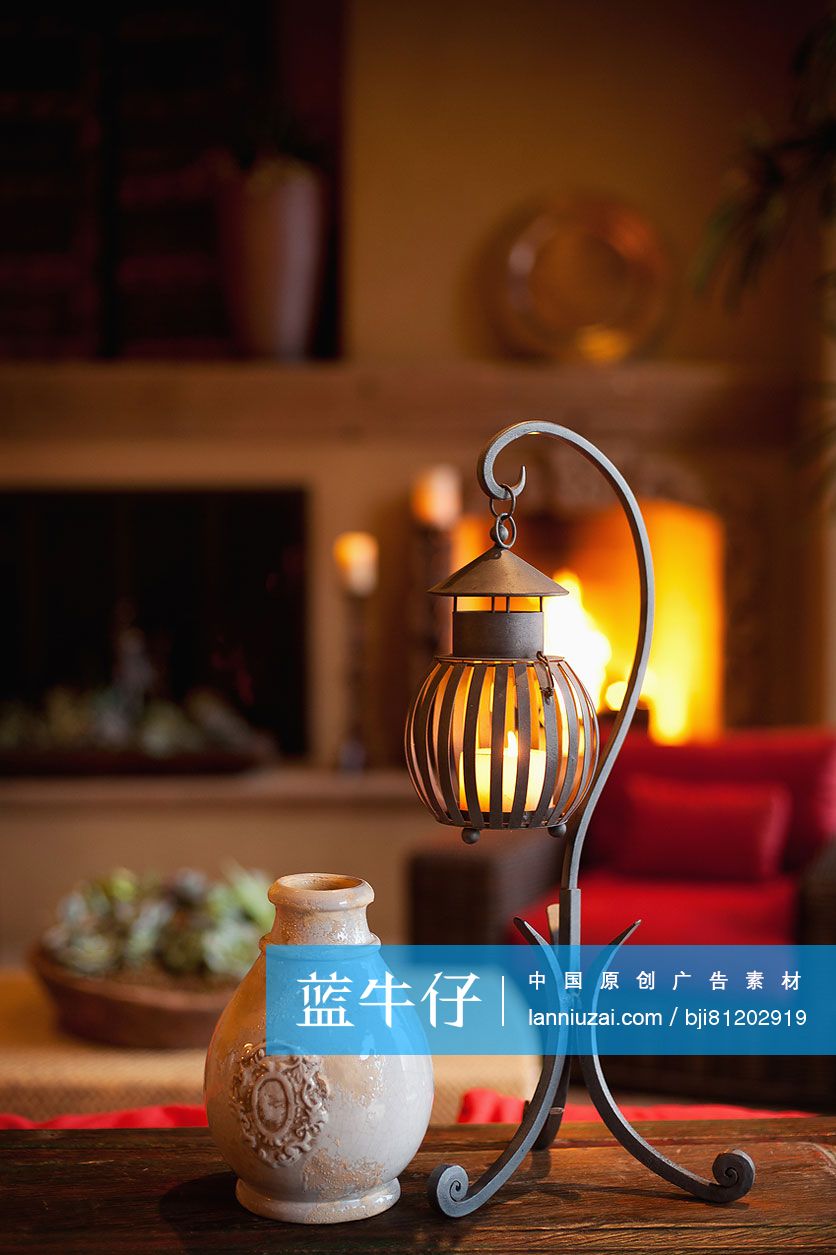 Pot with candle lantern on table against lit fireplace in living room at home; Scottsdale; USA