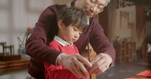 Chinese grandfather and grandson writing calligraphy on couplets,4K