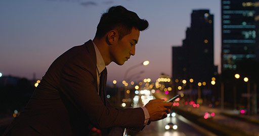 Young Chinese businessman using smartphone outdoors,4K
