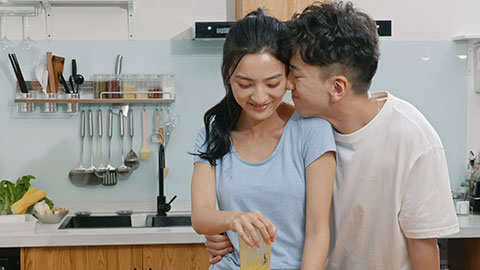 Happy young Chinese couple using juicer in kitchen,4K