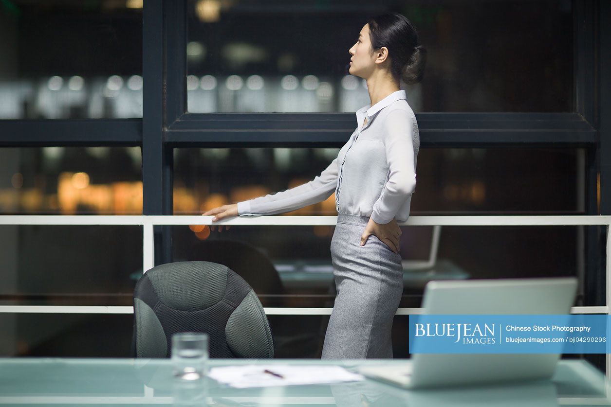 Young chinese businesswoman looking through window high res stock photo