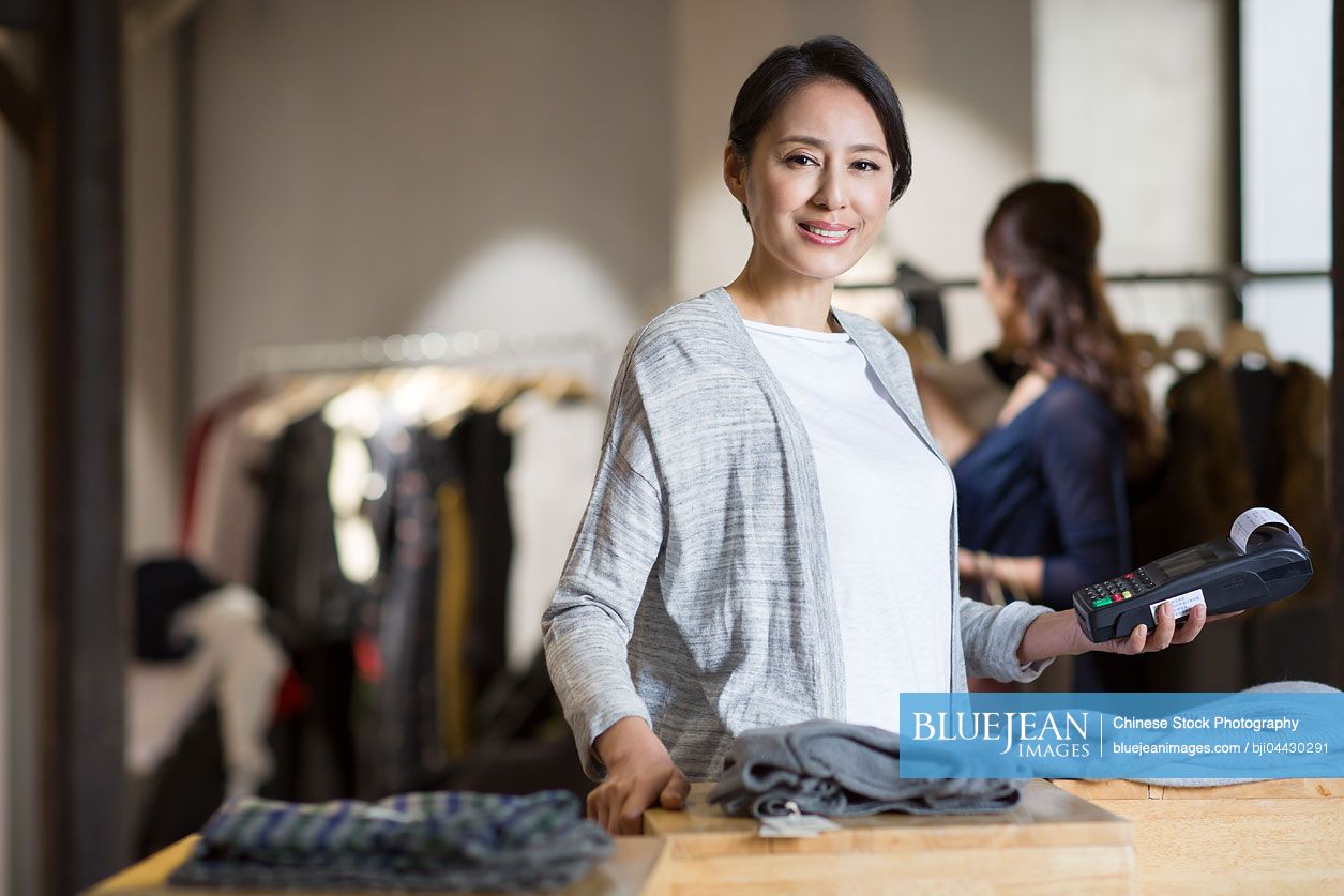 Chinese clothing store owner with credit card reader