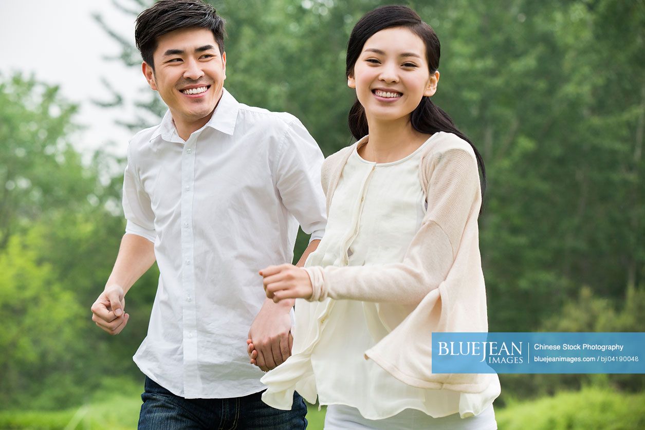 Happy young Chinese couple holding hands running