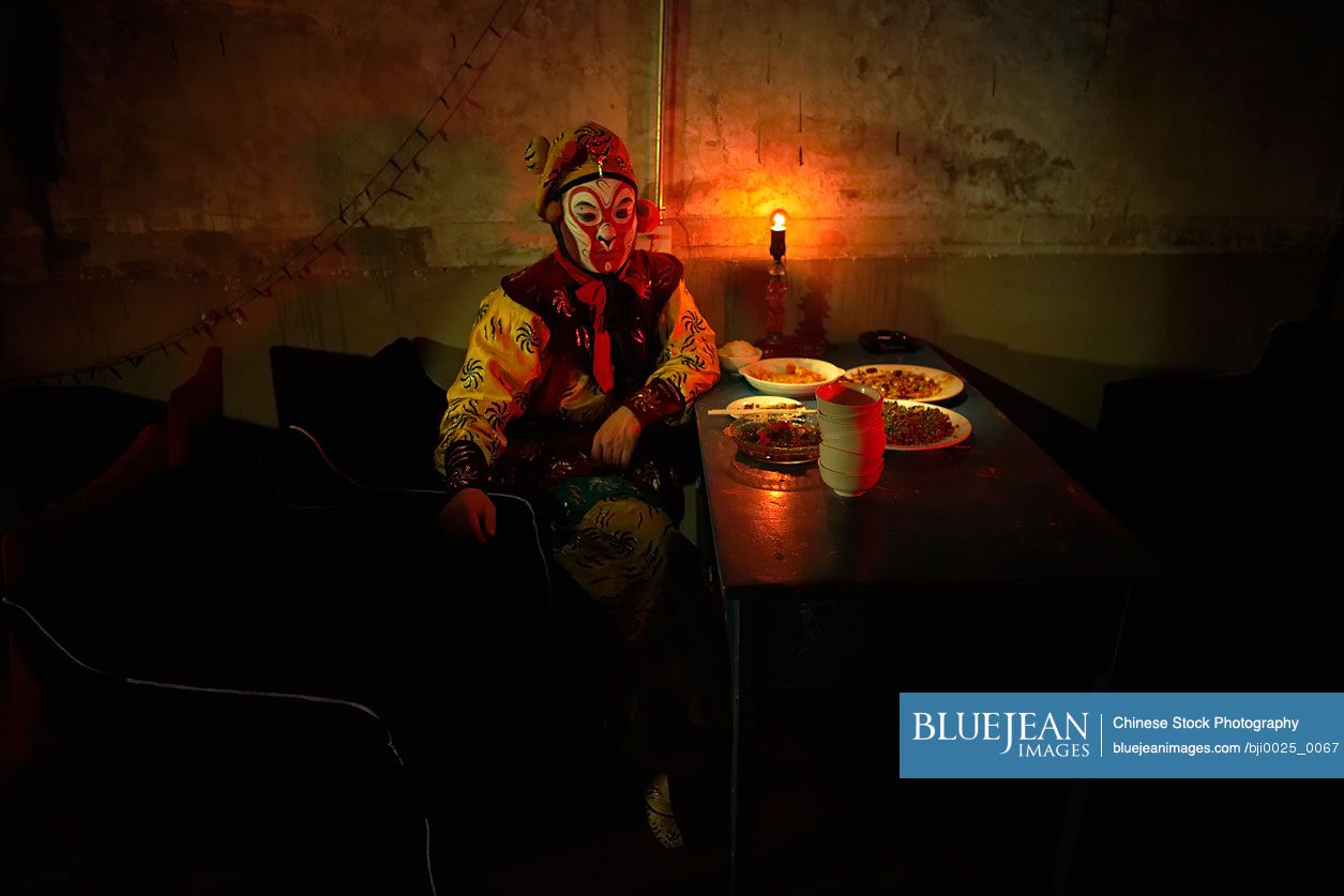 Chinese Man In Ceremonial Costume Sitting At Table With Food