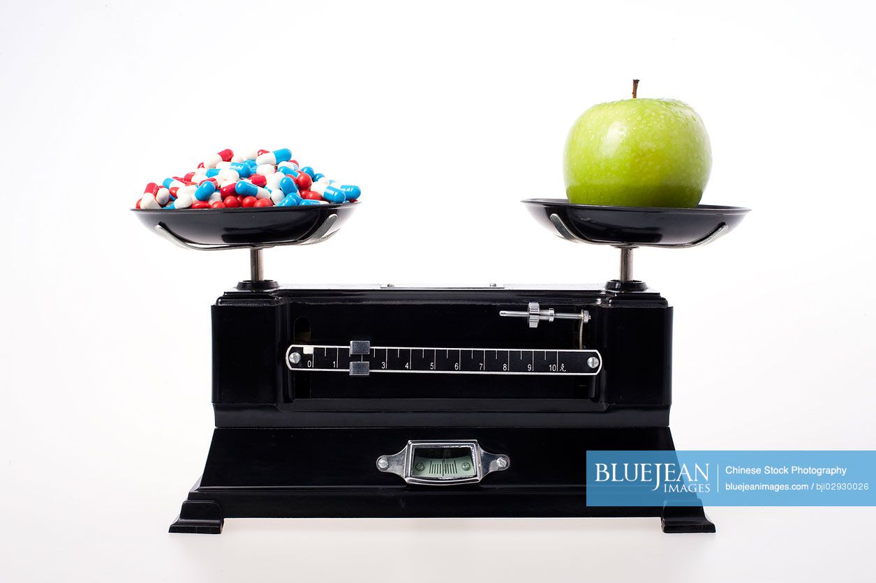 An apple and a lot of pills on weight scale