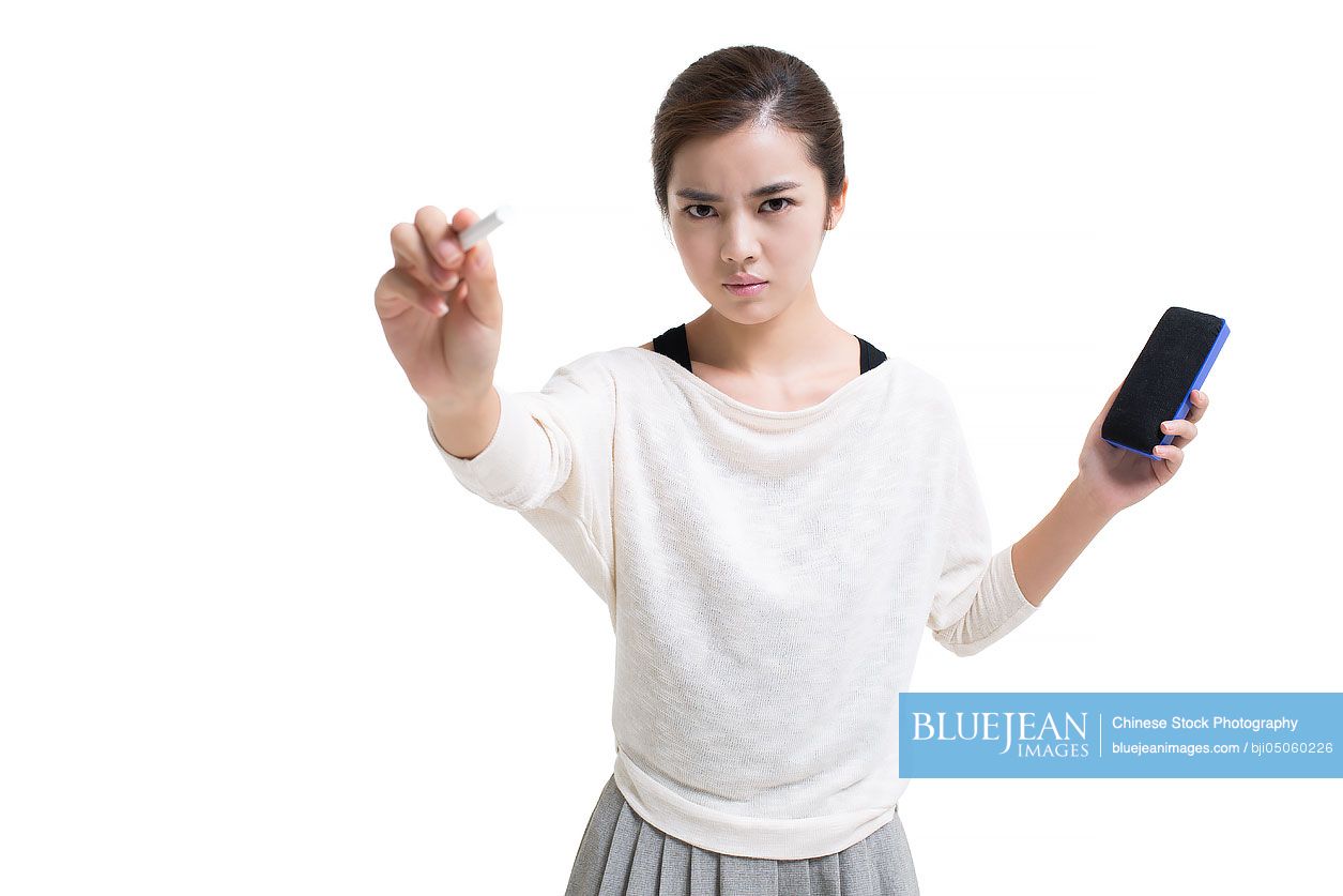 Angry young female Chinese teacher writing with chalk