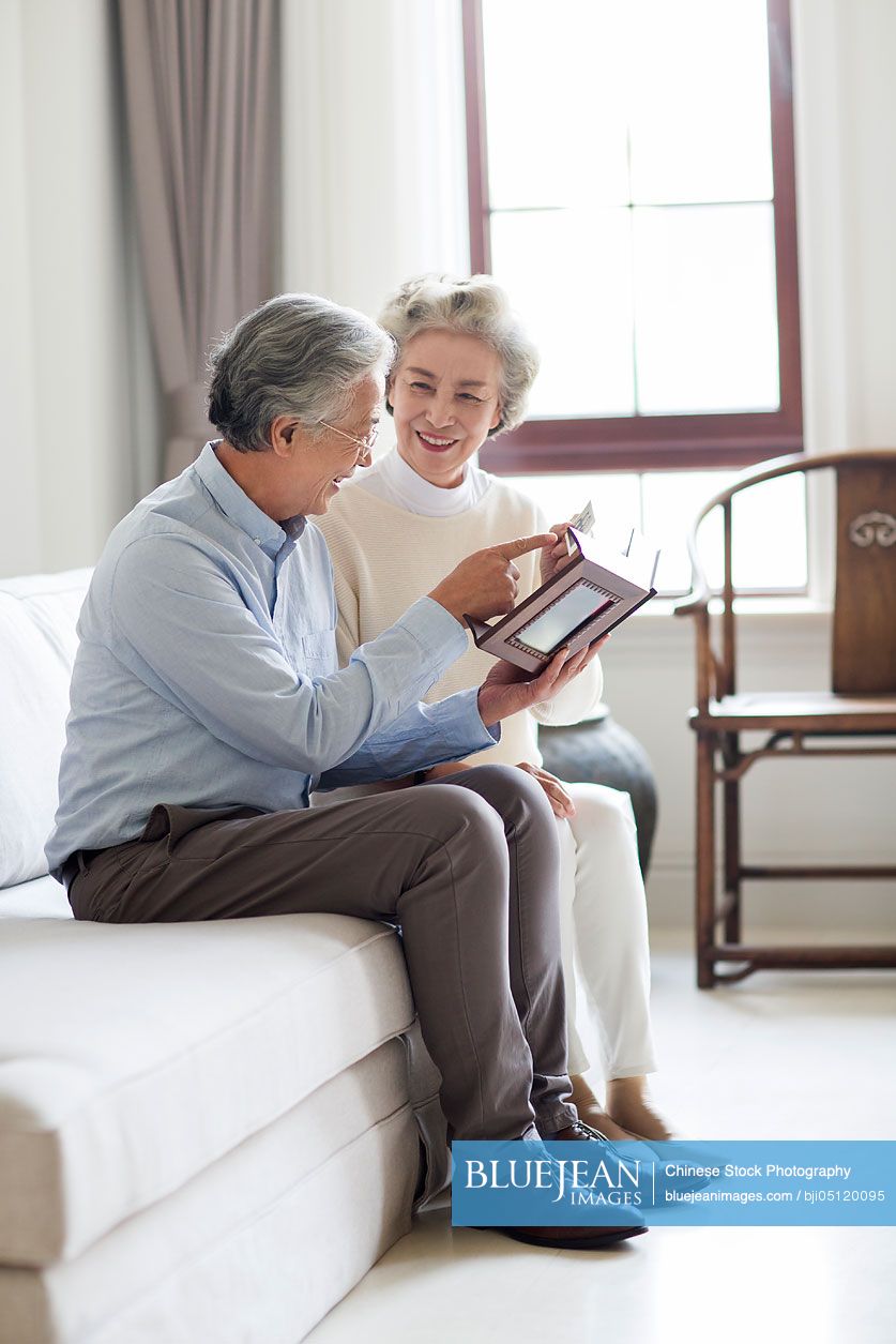 Happy senior Chinese couple looking at photo album
