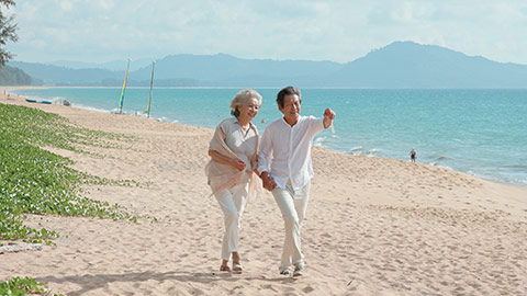 Happy senior Chinese couple walking on beach,4K