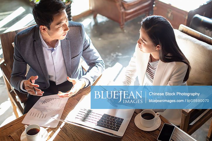 Young Chinese business people talking in coffee shop