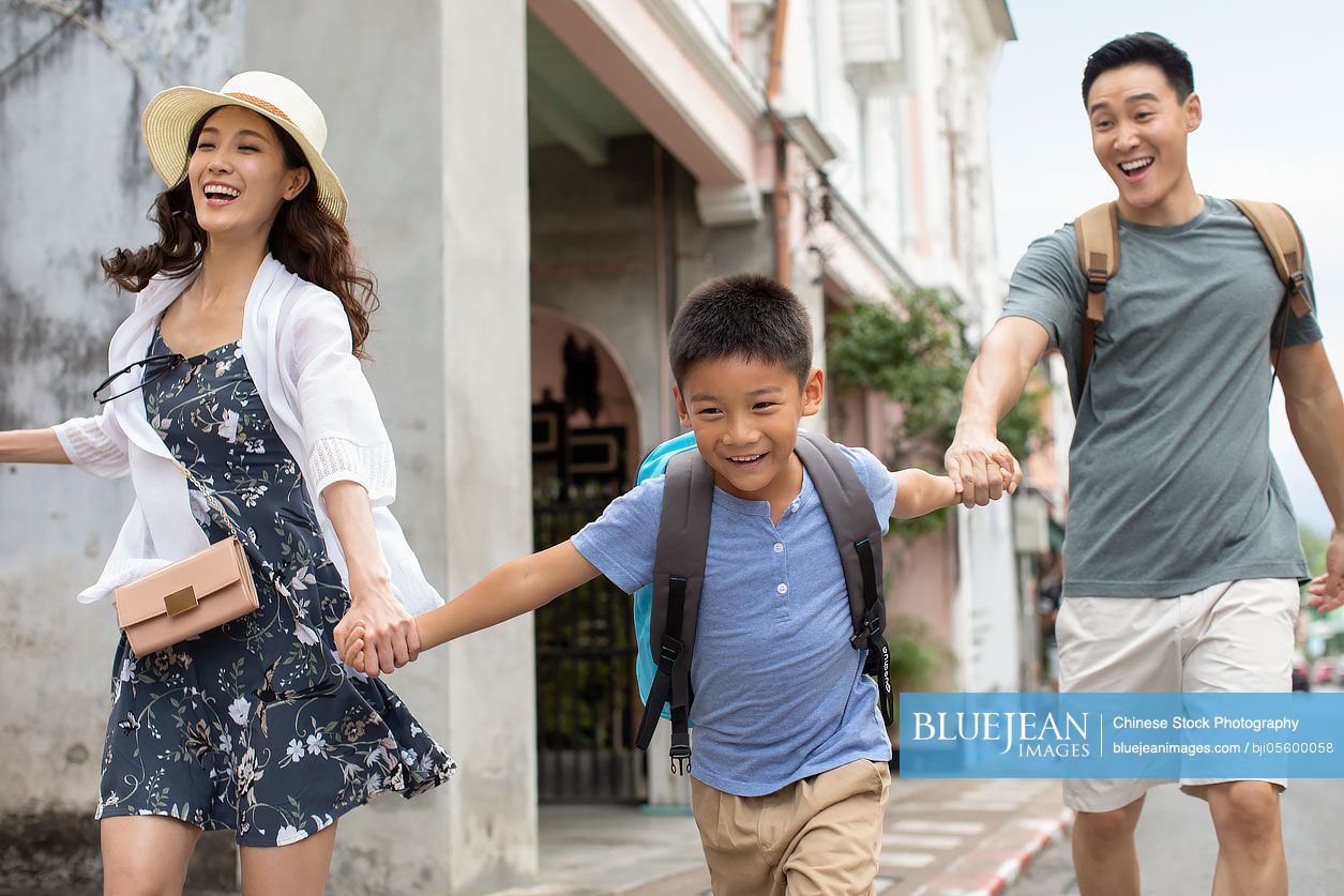 Happy young Chinese family running on street