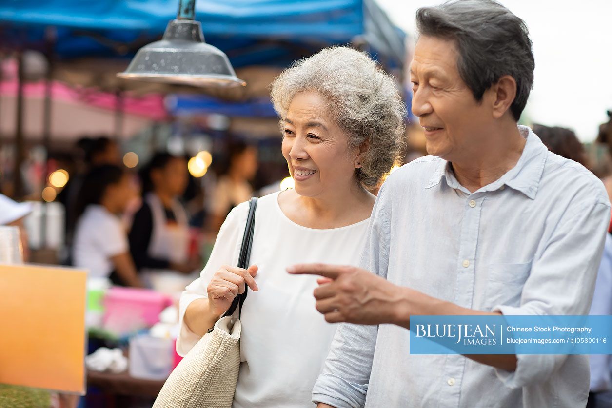 Happy senior Chinese couple relaxing in street market