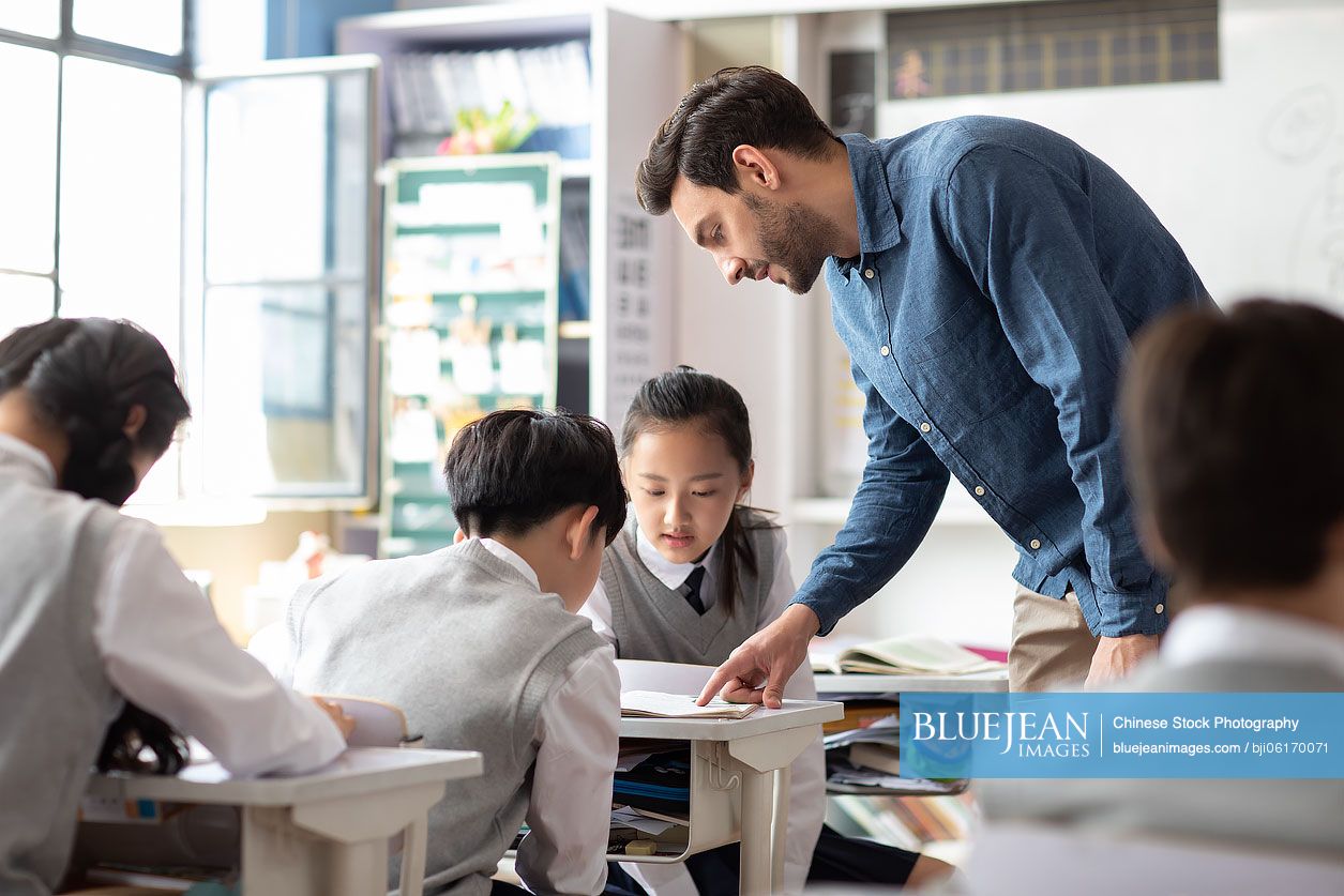 Young teacher helping students in classroom