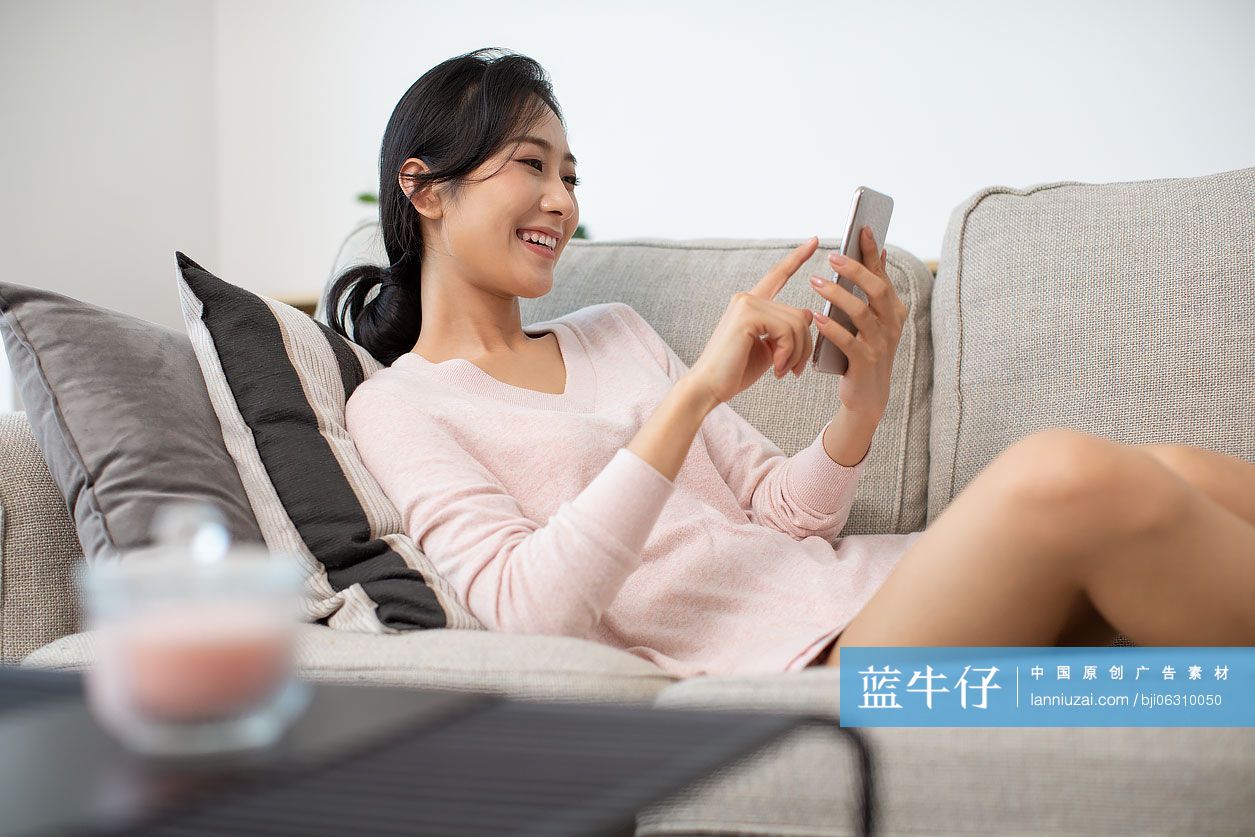 快乐年轻女士在家使用手机