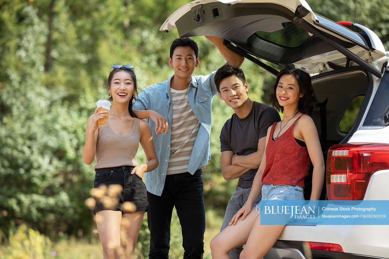 Happy young Chinese friends enjoying road trip