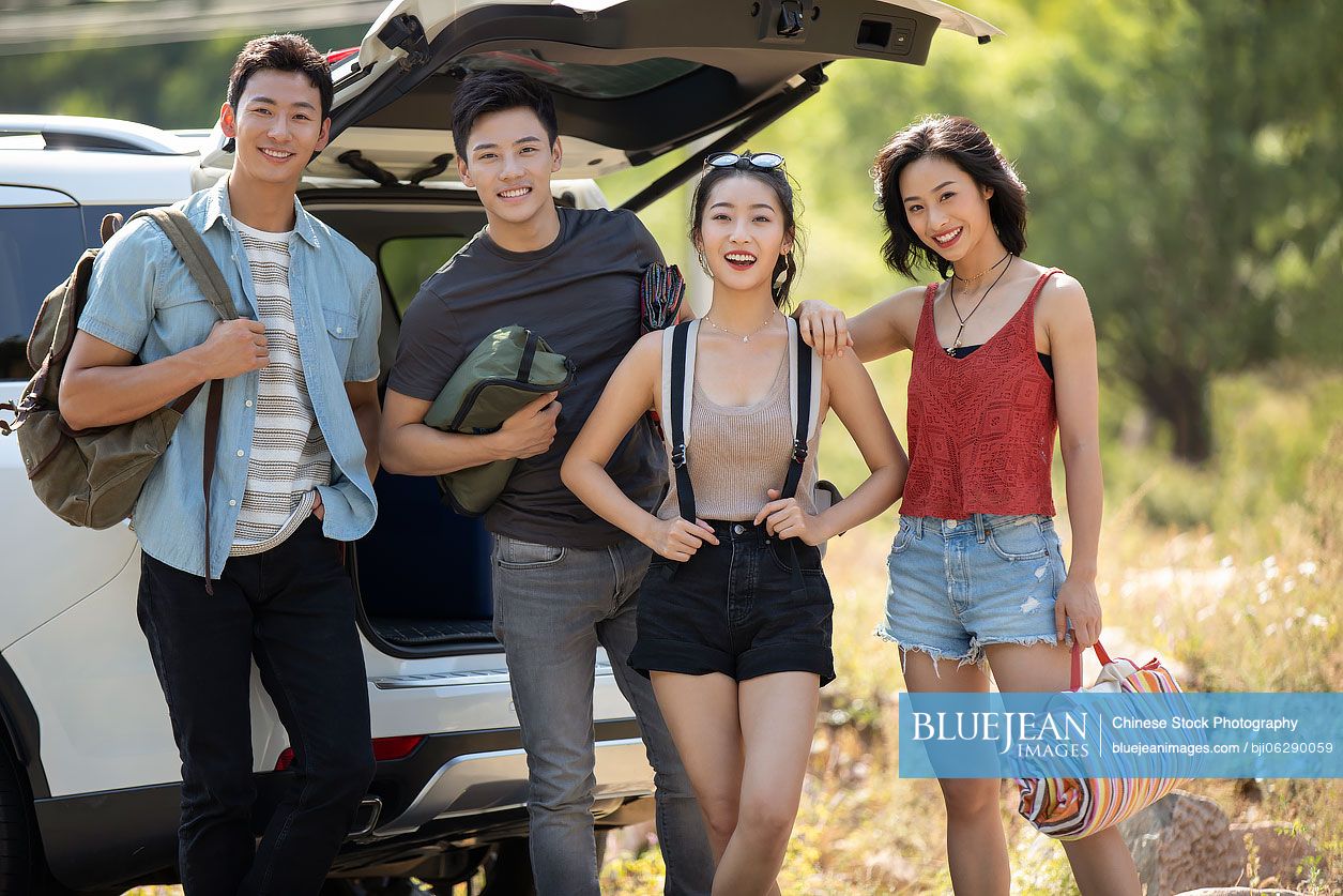 Happy young Chinese friends camping outdoors