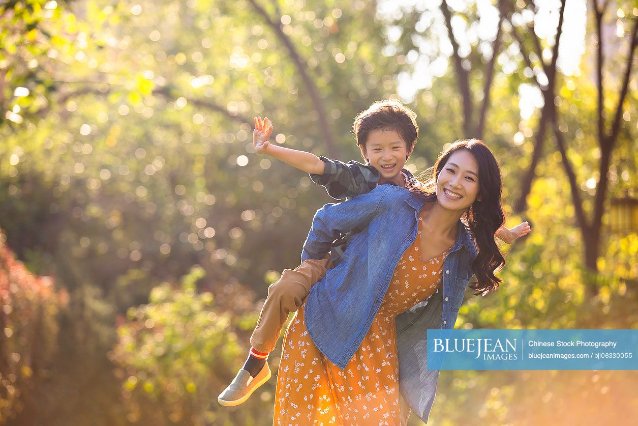 Happy Chinese mother and son playing in park