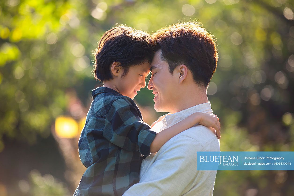 Happy Chinese father and son relaxing in park