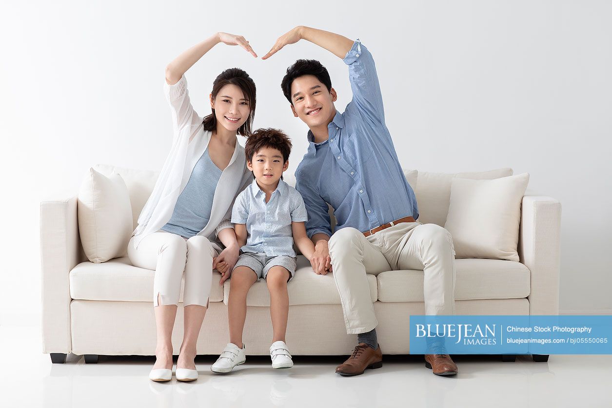 Cheerful young family sitting on sofa