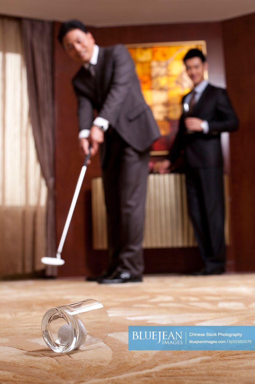 Chinese businessmen playing golf in a luxurious room