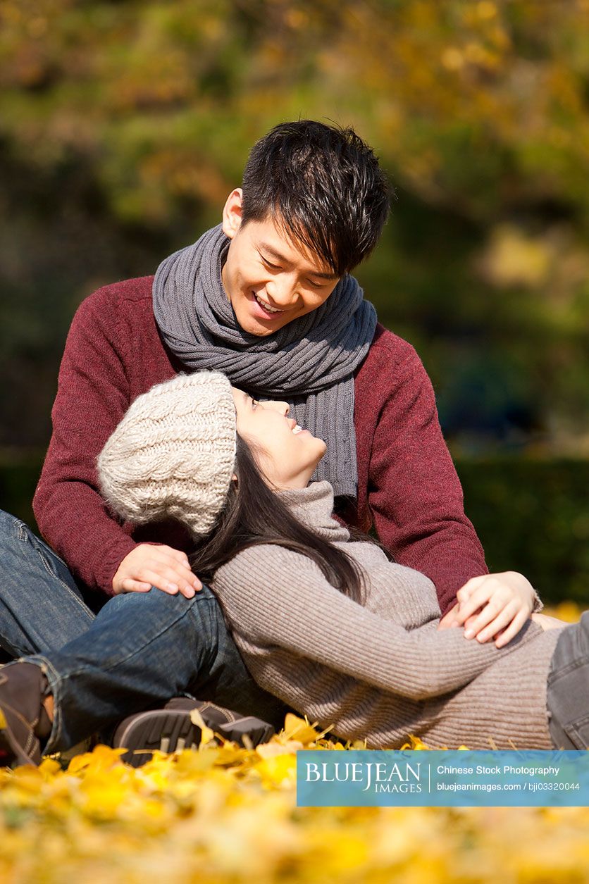 Sweet Chinese college couple looking into each other's eyes under the autumn sunshine