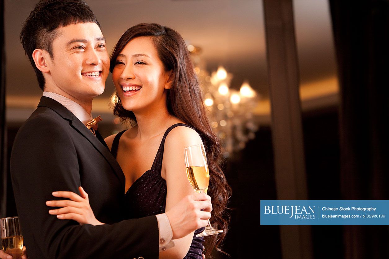 Young Chinese couple having champagne in a luxurious room