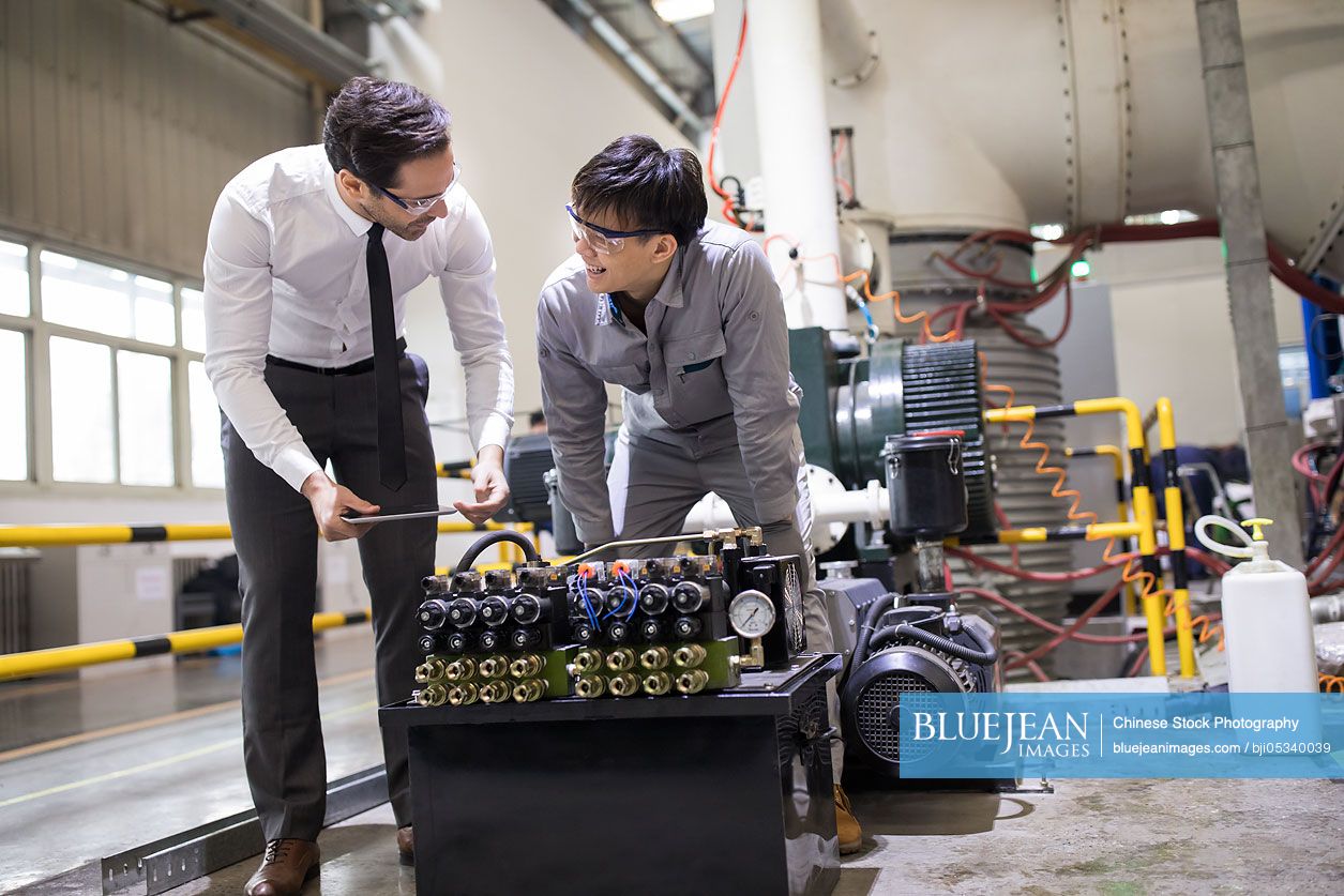 Businessman and engineer checking machine in the factory