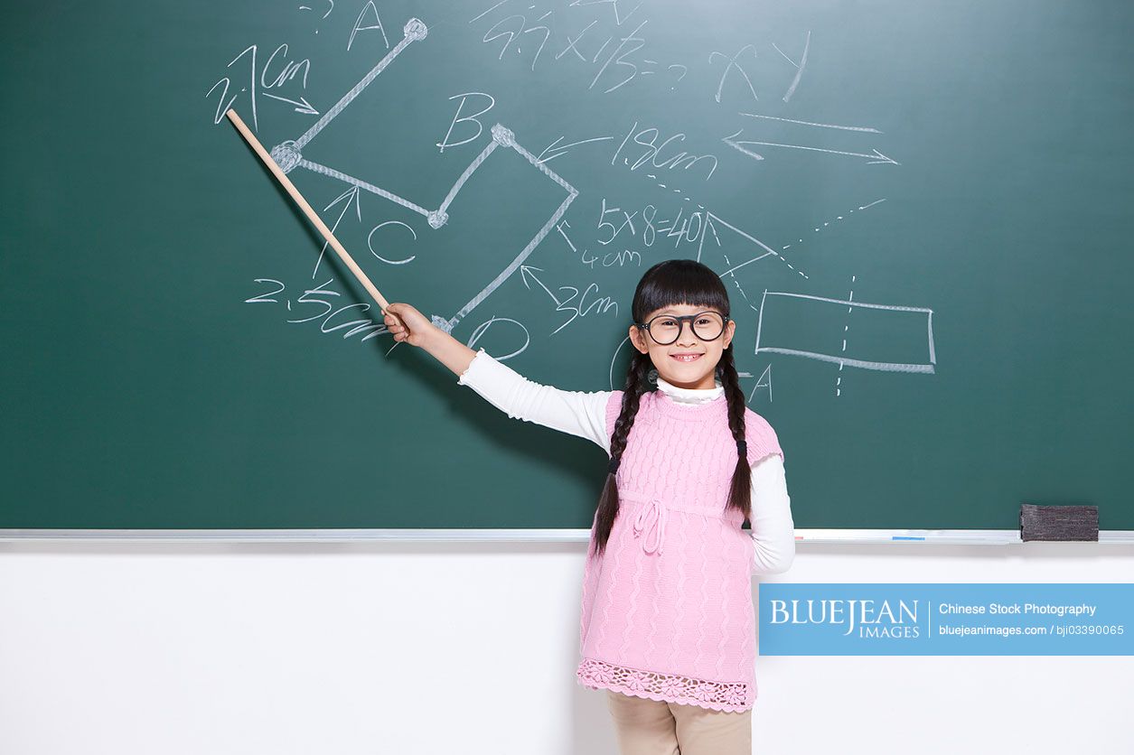 Humorous little Chinese girl playing Chinese teacher in classroom
