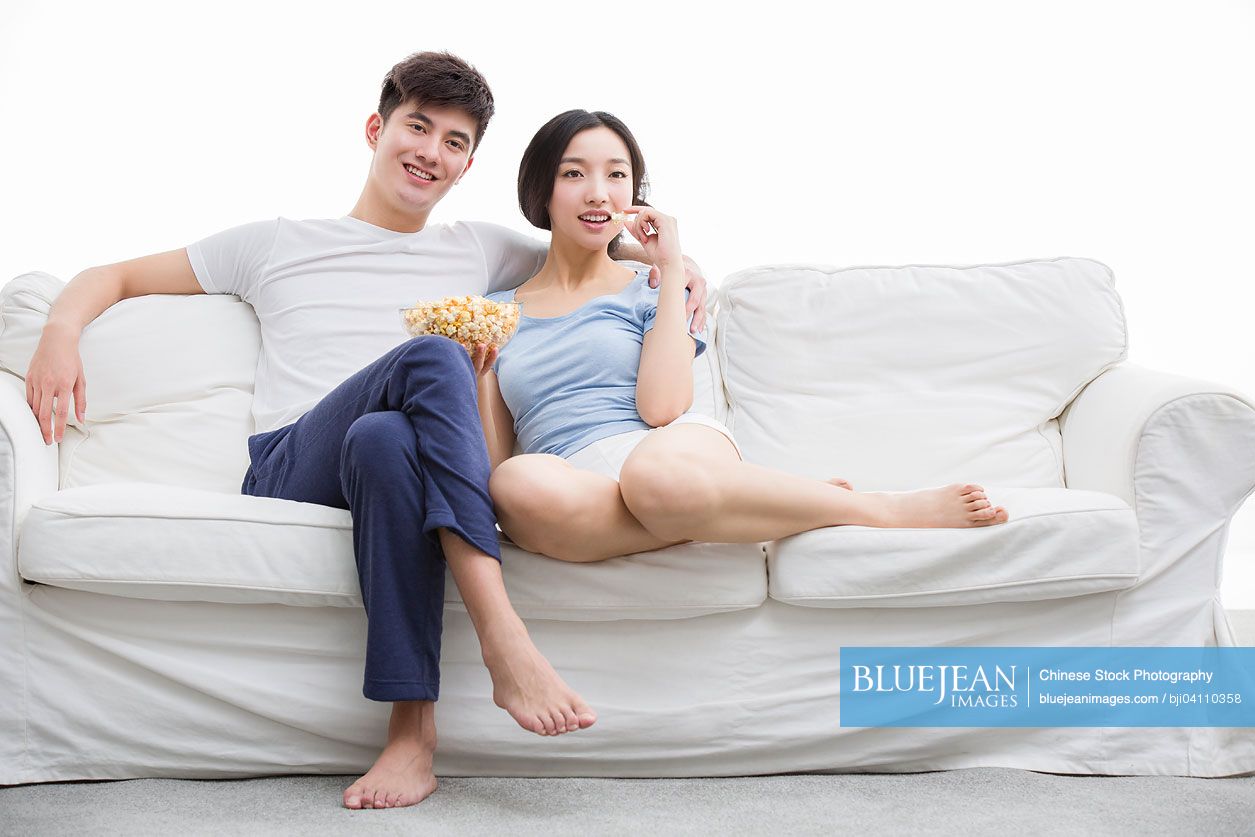 Young Chinese couple watching movie in living room