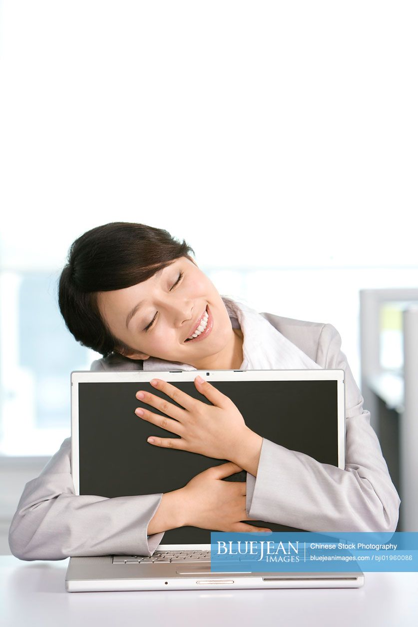 Chinese office worker hugging her computer