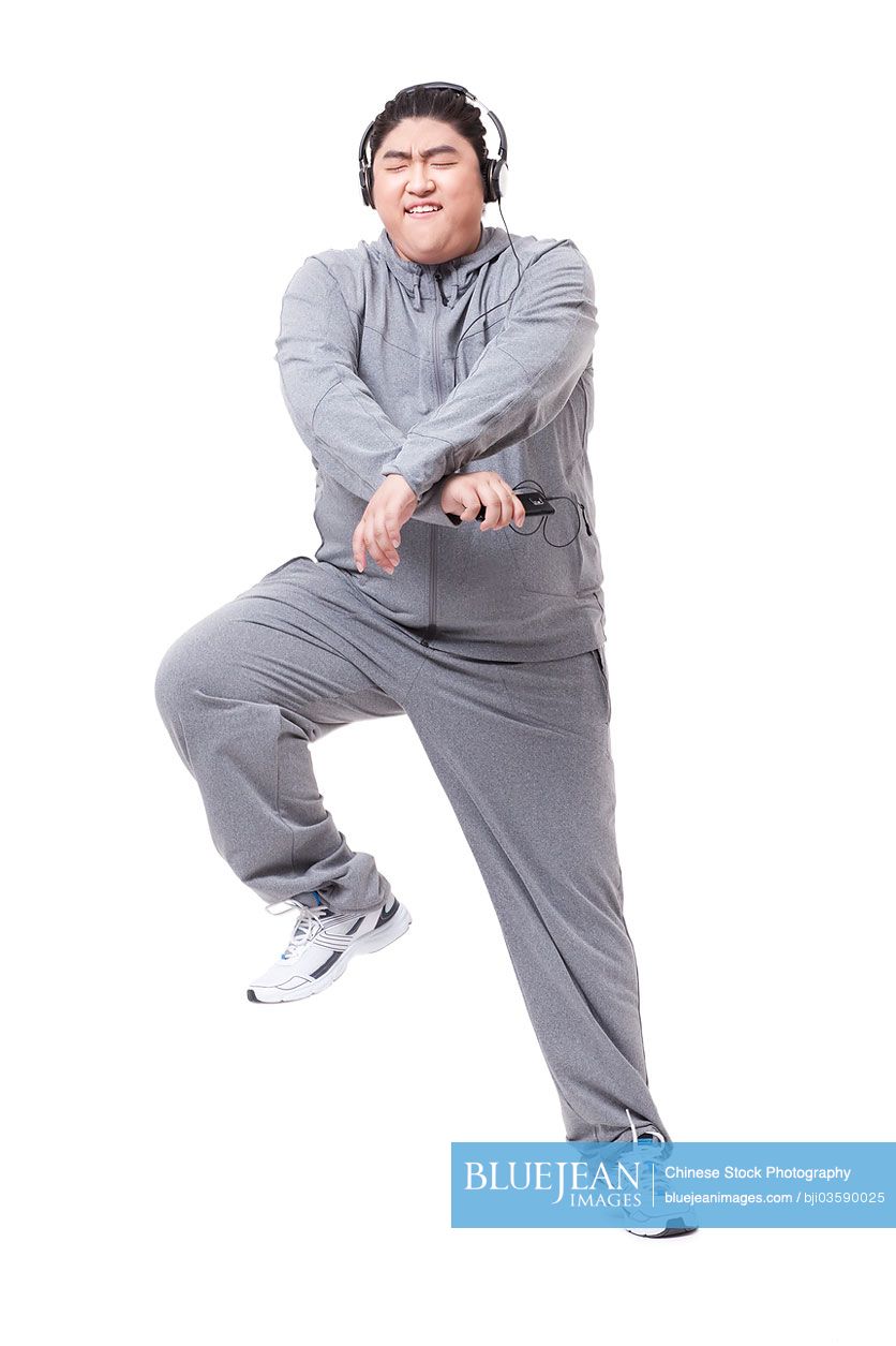 Fashionable Chubby Chinese man listening to music and dancing