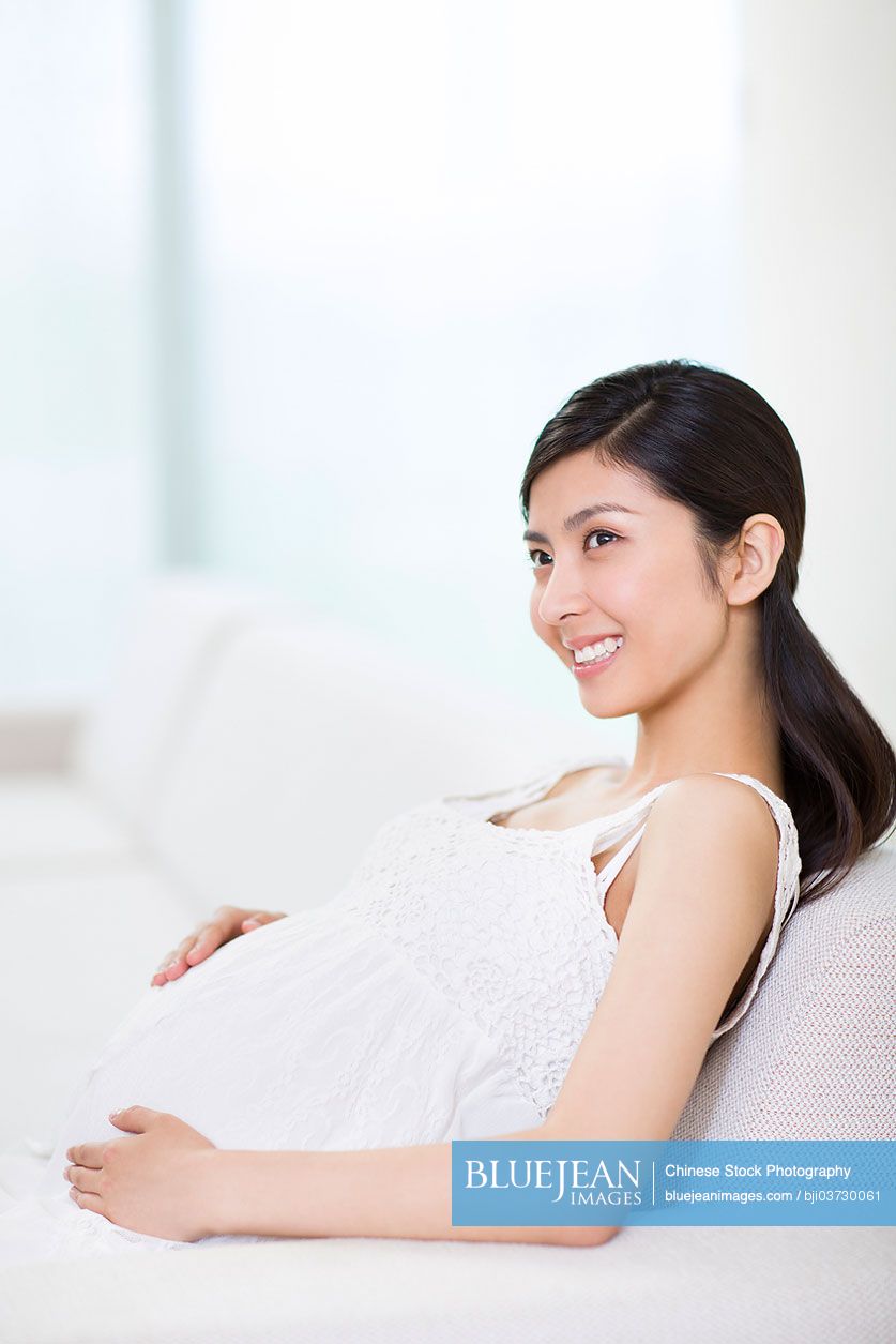 Pregnant Chinese woman sitting in sofa