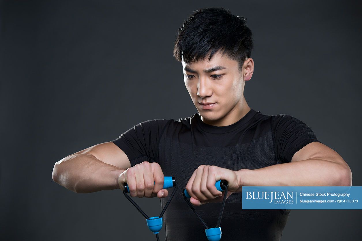 Young Chinese man exercising with resistance band