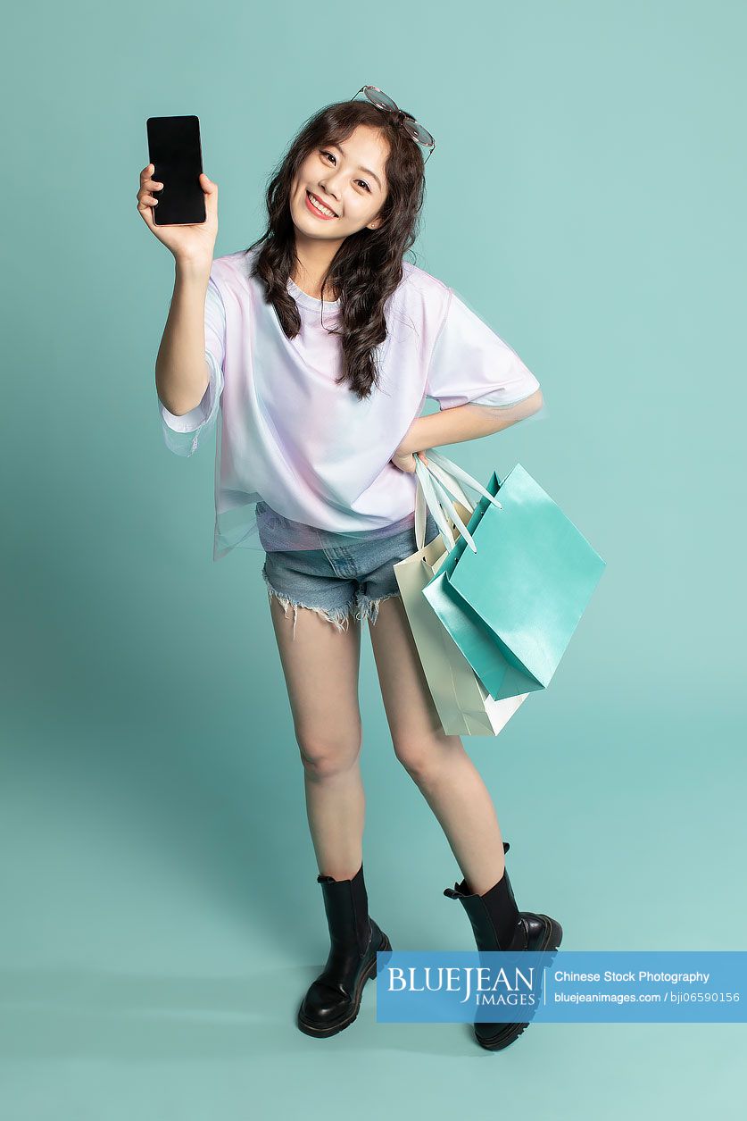 Studio shot of cute young Chinese woman shopping