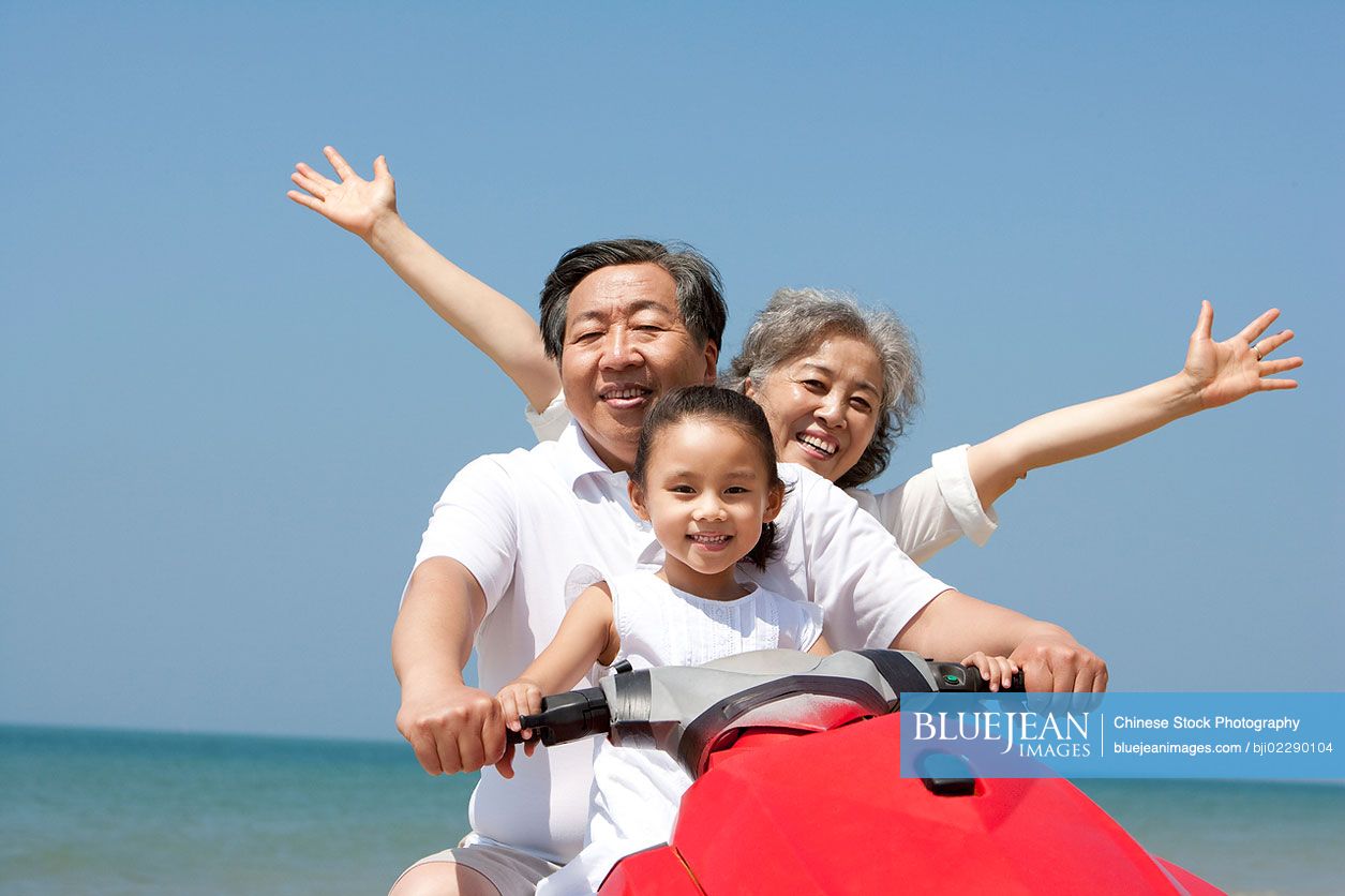 Chinese grandparents and granddaughter riding on a jet ski