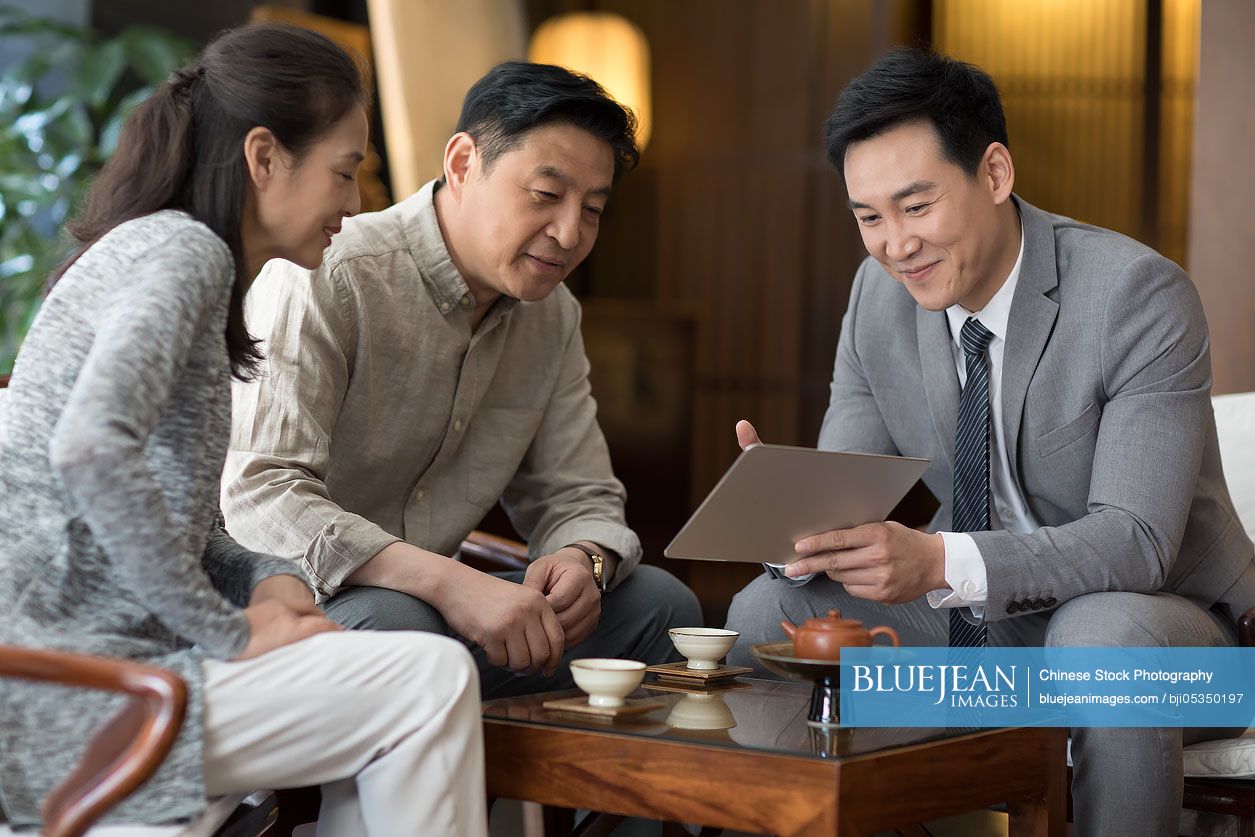 Confident Chinese financial consultant talking with mature couple