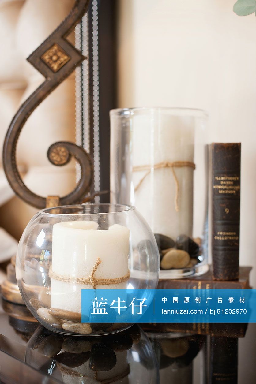 Close-up of lamp stand with candles; and books on console table at home