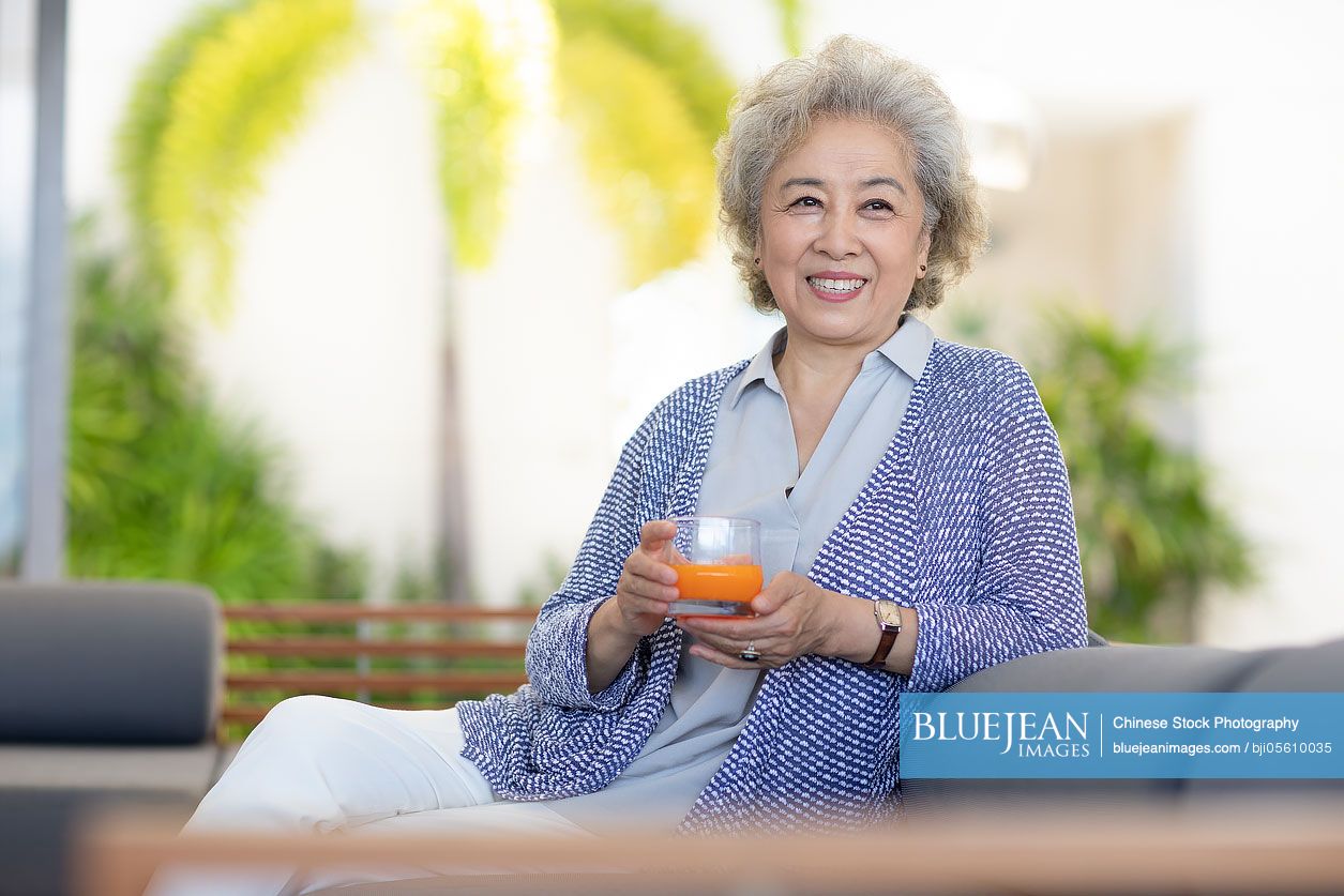 Happy senior Chinese woman relaxing in hotel room