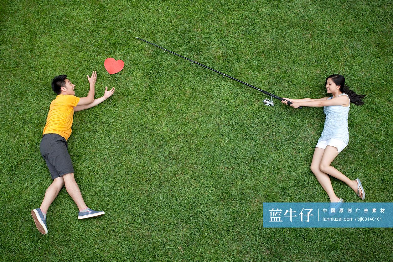 创意情侣在草地上模仿钓鱼
