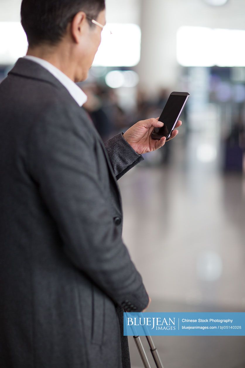Chinese businessman using smart phone in airport