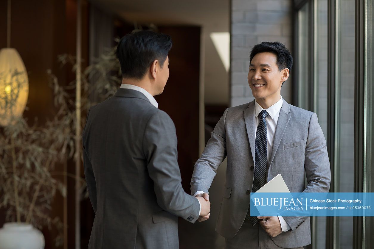 Cheerful Chinese businessmen shaking hands