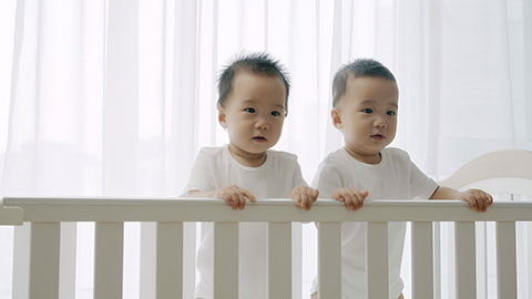 Two twin babies playing in their crib