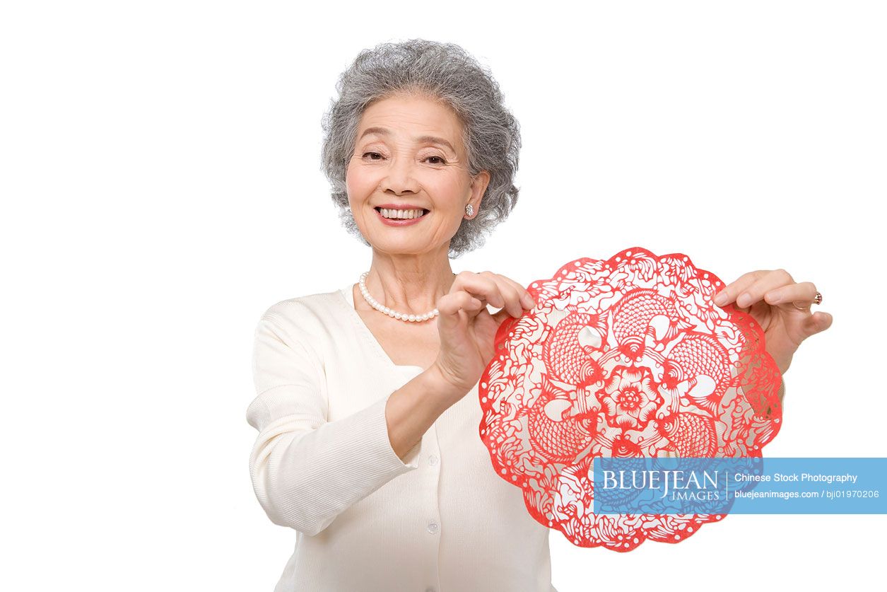 Senior Chinese woman holding traditional paper cutting