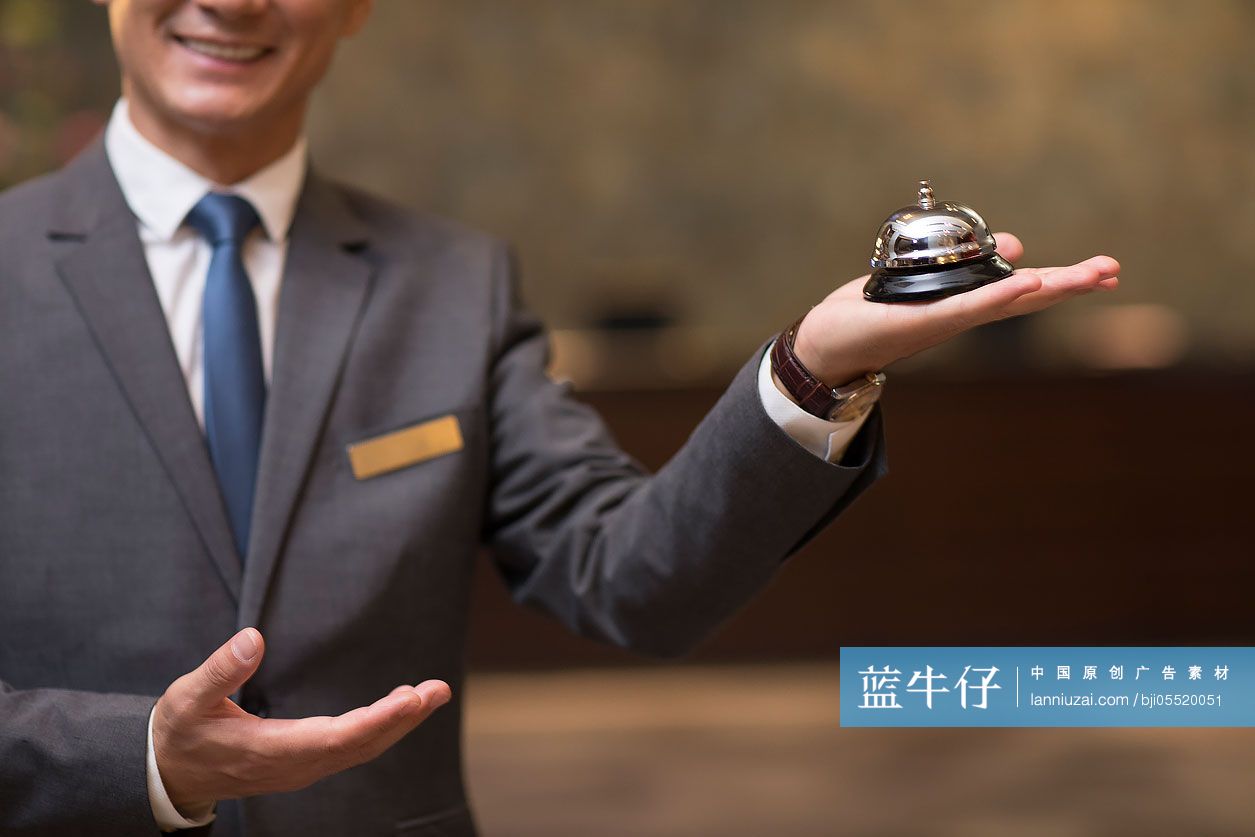 自信的酒店经理拿着服务铃