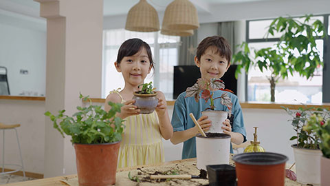 Girl and boy enjoy potting plants together at home