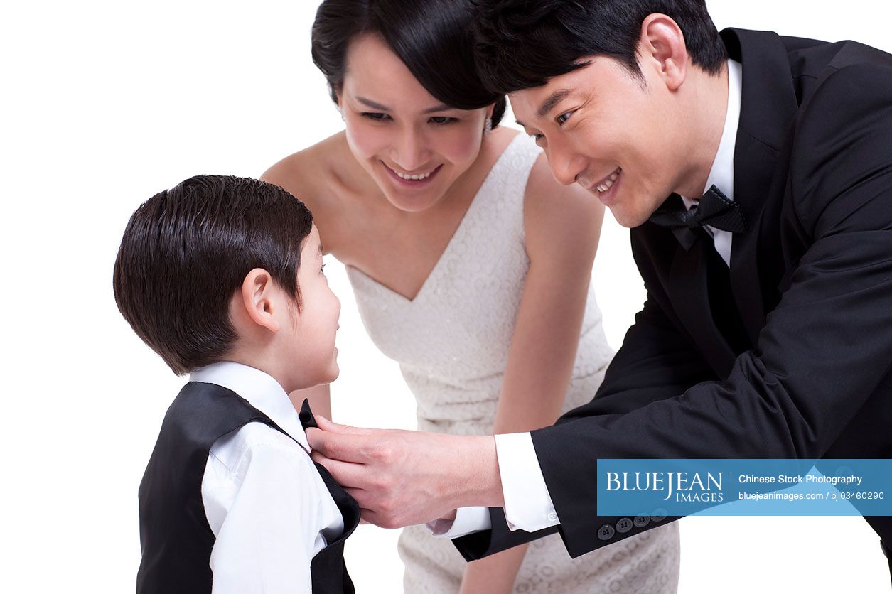 Smiling Chinese father adjusting bow tie for little son