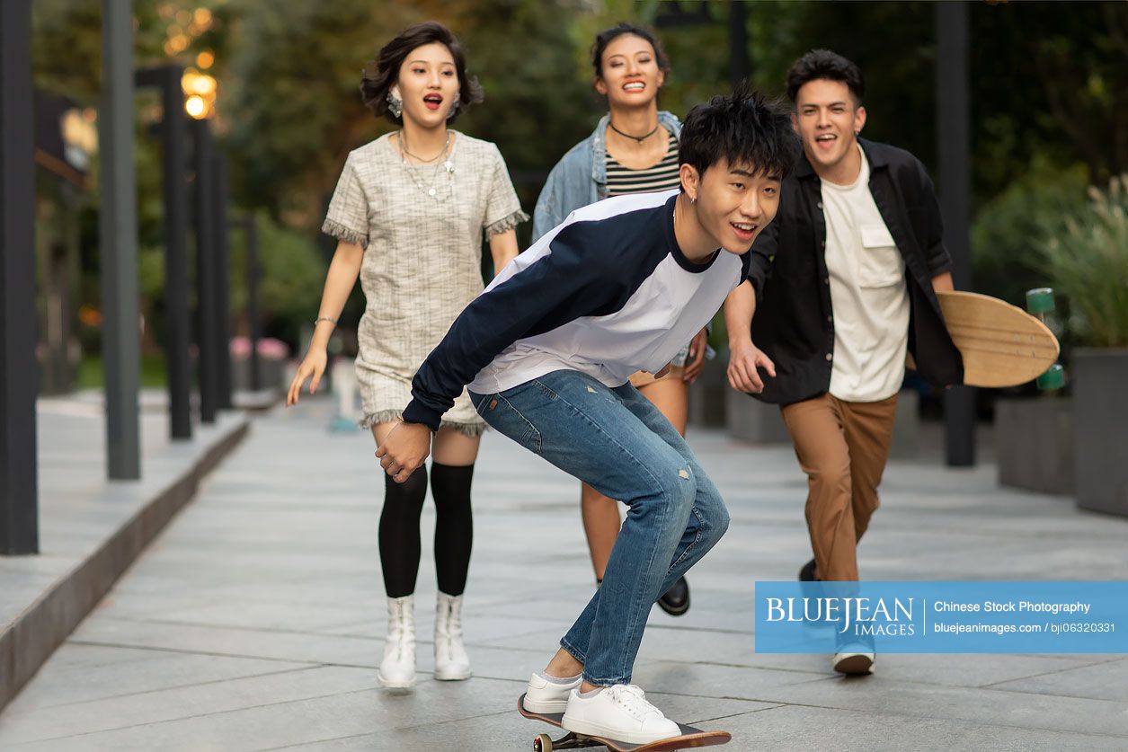 Fashionable young Chinese people enjoying skateboarding outdoors