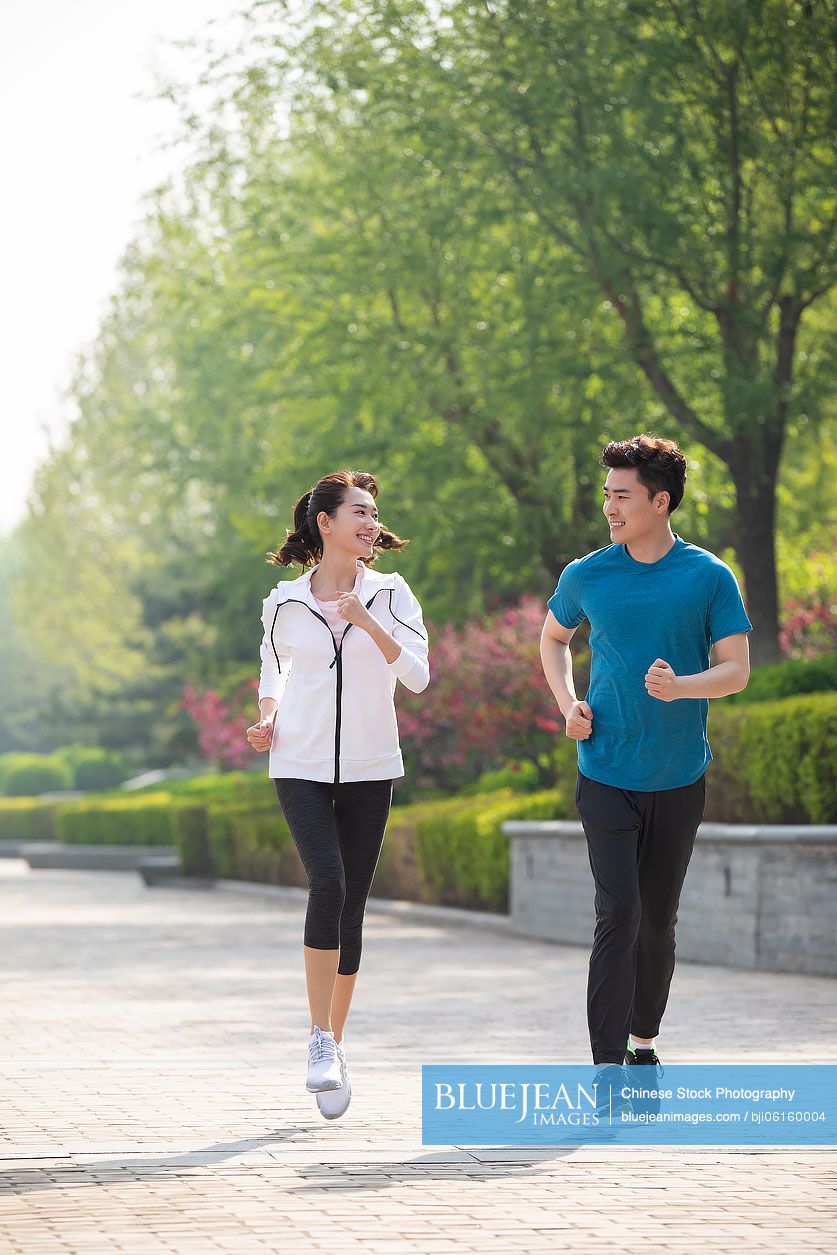 Happy young Chinese couple running in park